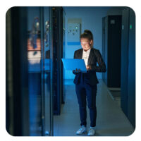 IT-lerin arbeitet am Laptop im Serverraum
