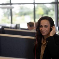 Mitarbeiterin, die mit einem Headset am Schreibtisch sitzt.