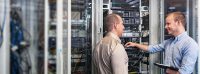 Zwei IT-Spezialisten stehen im Serverraum und besprechen sich