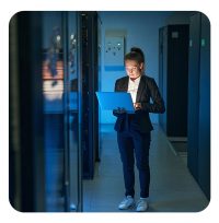 IT-lerin arbeitet am Laptop im Serverraum