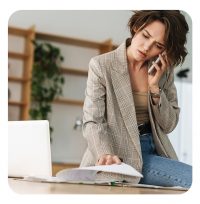 Frau am Telefon während sie durch Dokumente sucht