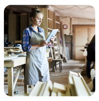 Telefonservice Handerwerker - Handwerkerin in der Holzwerkstatt am Tablet