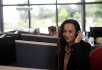 Mitarbeiterin, die mit einem Headset am Schreibtisch sitzt.